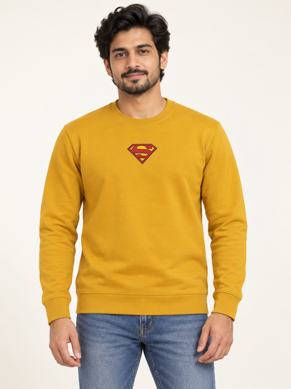Mustard long sleeve crew neck sweatshirt with a small red and yellow shield chest graphic, on an adult model.